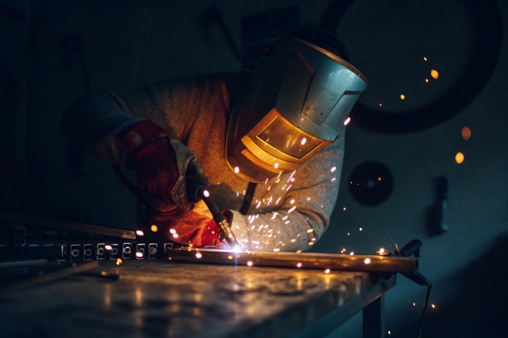 Man worker welding metal with welding machine in a factory or workshop